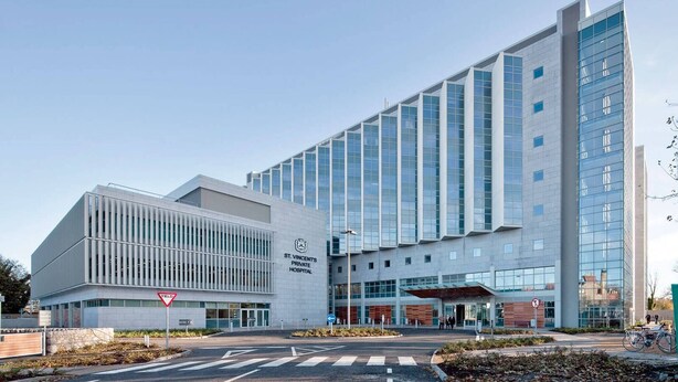 Um edifício hospitalar moderno com entrada destacada e céu claro.
