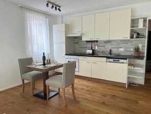 A modern kitchen with white cabinets, a wooden dining table, and two chairs. - Hideaway in Strobl with bathing area and breakfast at partner hotel (Strobl)