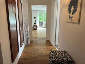 A hallway with wooden flooring, a zebra-patterned ottoman, and a framed artwork on the wall. - Hideaway in Strobl with bathing area and breakfast at partner hotel (Strobl)