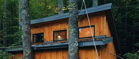 Una cabaña de madera con balcón, rodeada de árboles.