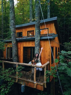 A wooden cabin with a balcony, surrounded by trees.