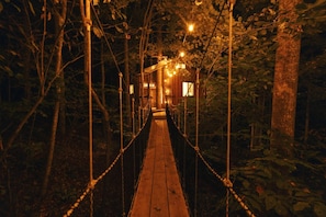 Eine Holz-Hängebrücke in bewaldeter Landschaft mit Lichterketten.