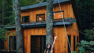 A wooden cabin with a balcony, surrounded by trees.