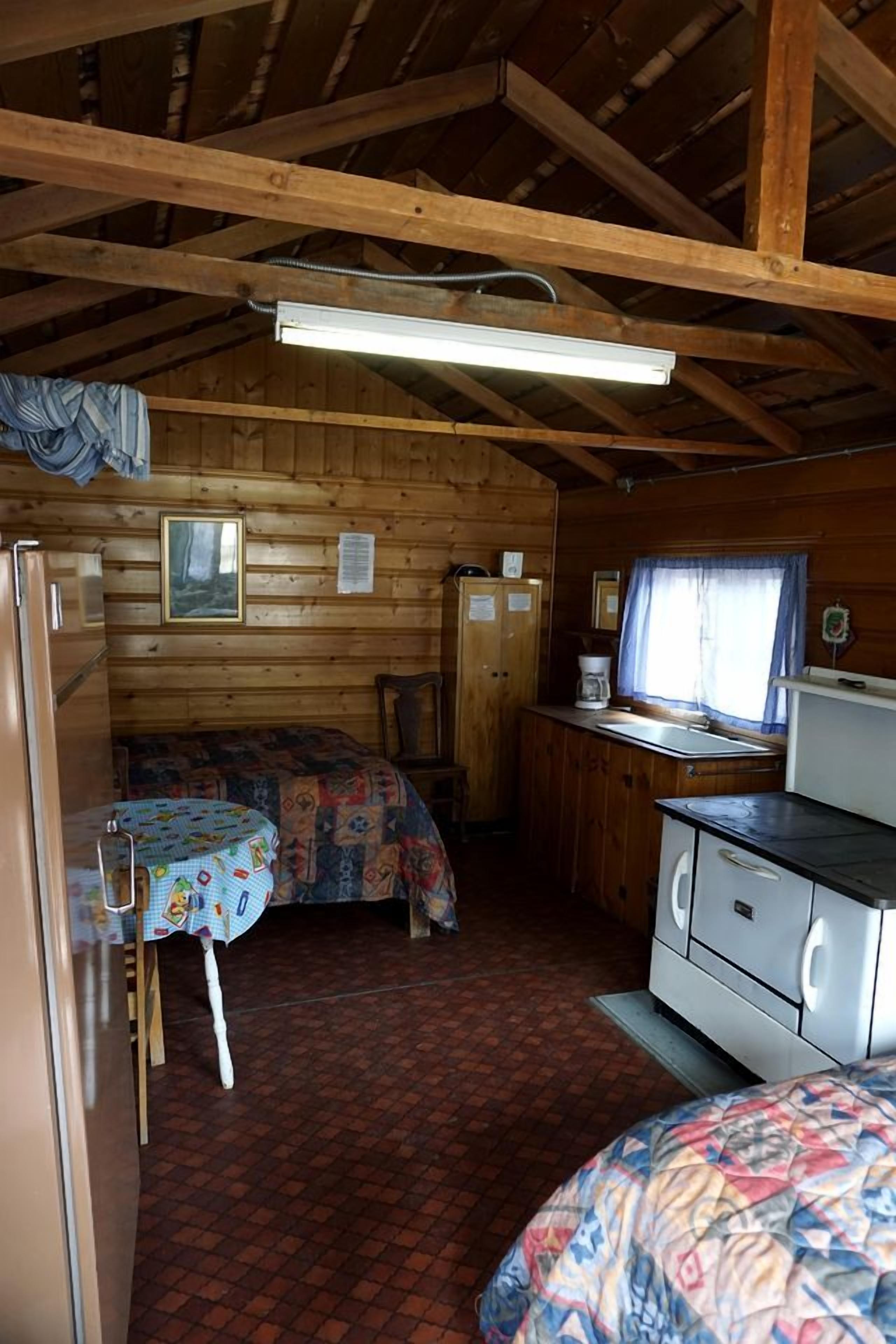Una cabaña compacta con kitchenette, una cama, una mesita y un ventanal.