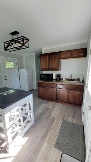 A compact kitchen with wooden cabinets, a microwave, and a coffee maker.