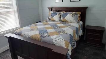 A bedroom with a bed, a ceiling fan, a nightstand, and a window.