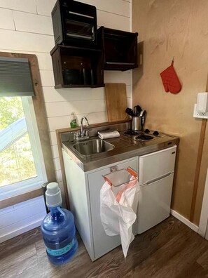 A compact kitchen with a sink, a small refrigerator, and a water dispenser. - Cozy Modern Tiny Retreat with Stargazing & Yoga Dome Access Near Yosemite Tioga Pass, Groveland, California (Groveland)