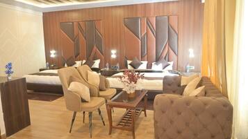 A hotel room with a bed, two sofas, a coffee table, and a decorative wall panel.