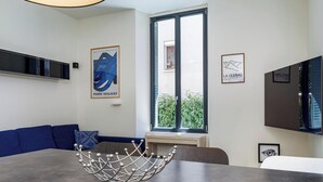 Ein moderner Essbereich mit einem blauen Sofa, einem Esstisch und Kunstwerken an den Wänden.