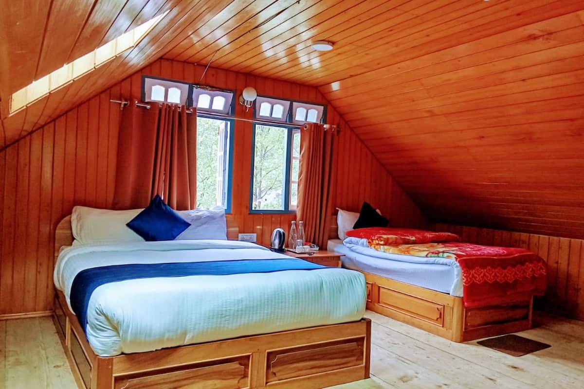 A wooden cabin bedroom with a large bed, a smaller bed, and a window.