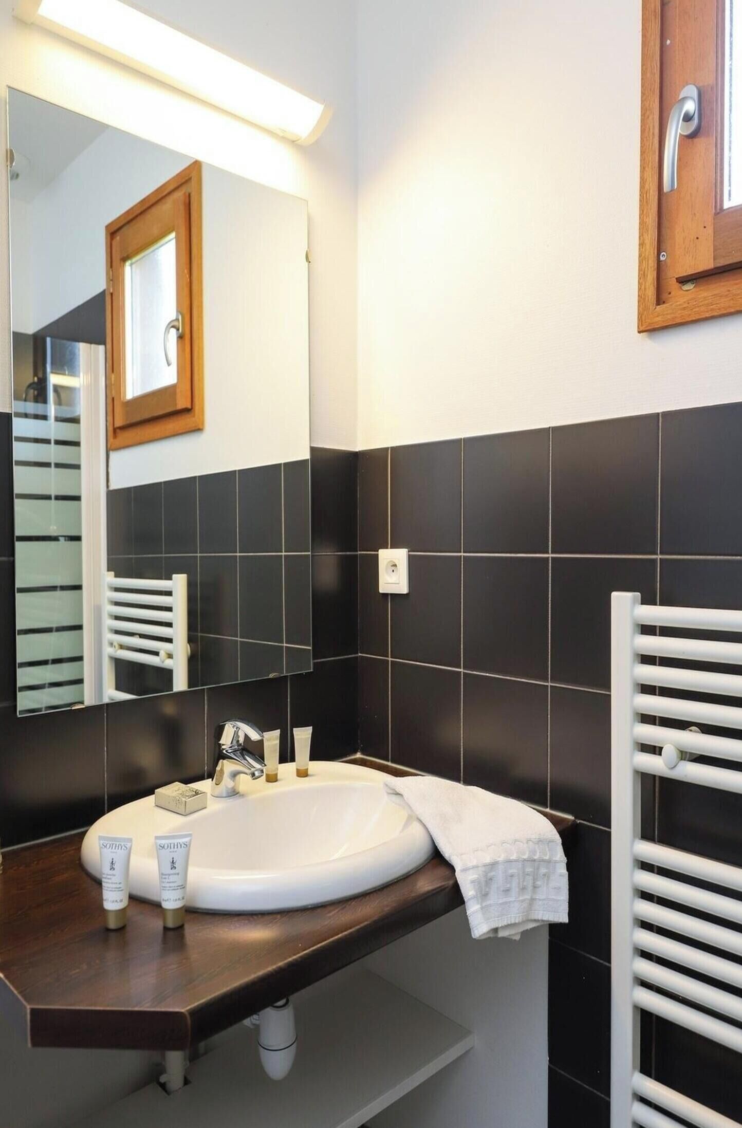 A bathroom with a white sink, a mirror, and black tiles.
