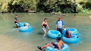 People floating on blue water tubes in a natural setting.