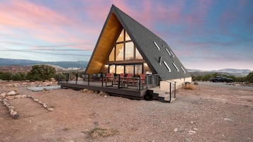 Un edificio moderno dalla forma triangolare, con ampie finestre e una terrazza con posti a sedere.