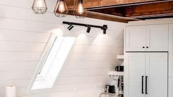 A modern kitchen with a large island, pendant lights, and a view of the outdoors.