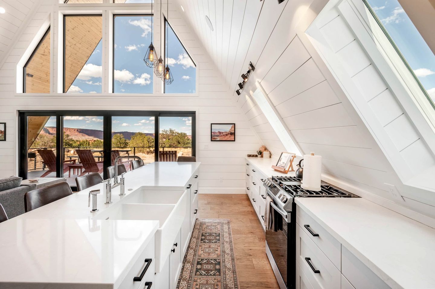A modern kitchen with a large island, white cabinetry, and a view of the outdoors.