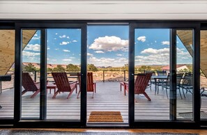 Una terraza con sillas y mesas, puertas de cristal amplias y vistas a un paisaje desértico.