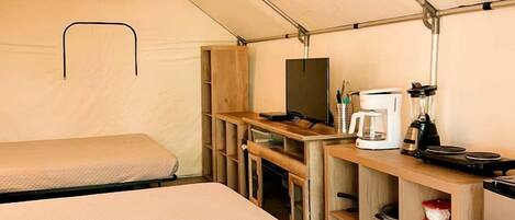A tent with two beds, a kitchenette, and a small table.