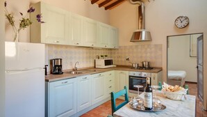A kitchen with light blue cabinets, a stove, a sink, and a dining table set with a bottle and glasses. - Apartments Florence - Canto dei Nelli (Firenze)