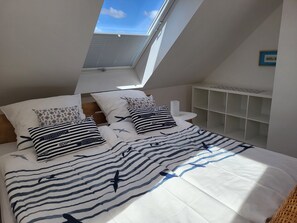 A bedroom with a skylight, striped bedding, and a white headboard. - Apartment 'Sea Escape on the Baltic Sea' on the Schwansen Peninsula (Dörphof)