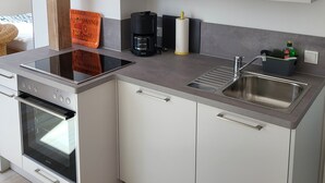 Eine moderne Küche mit weißen Schränken, einem Backofen, einer Kaffeemaschine und einem Spülbecken.