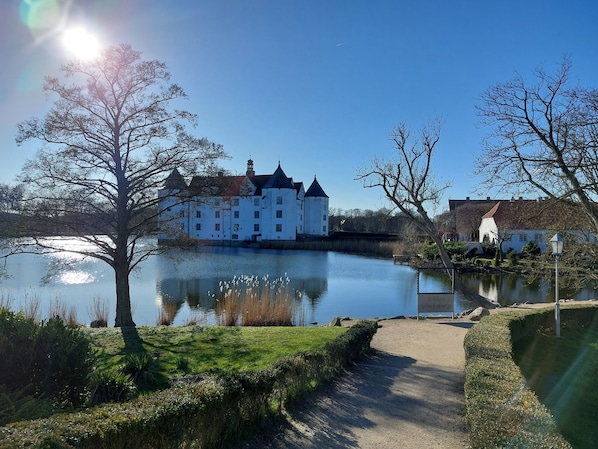 Een kasteel aan een rustig meer, met een heldere lucht.