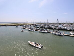 A marina with multiple boats docked, a small boat in the foreground, and a clear sky. - 50 Sea Road (Lymington)