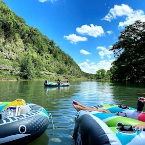 Une rivière où l’on peut faire du rafting sur des radeaux gonflables, et une personne allongée sur un de ces radeaux.