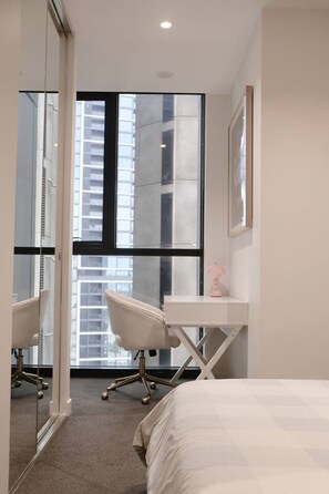 Ein modernes Hotelzimmer mit großem Fenster, Schreibtisch, Stuhl und Bett.