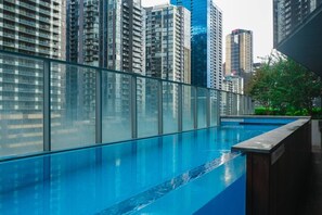 Ein Schwimmbecken mit Glasbarriere, umgeben von Hochhäusern.