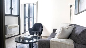 Ein modernes Wohnzimmer mit einer Couch, einem runden Couchtisch, einem Sessel und einer Stehlampe.