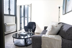Ein modernes Wohnzimmer mit einer Couch, einem runden Couchtisch, einem Sessel und einer Stehlampe.