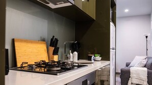 Eine kleine Küche mit einem Gaskochfeld, einem Holzer Schneidebrett und einem Spülbecken.