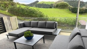 Ein moderner Außenbereich mit einer Sitzecke, einem Sofa, einem Tisch und einem Topfpflanzen.