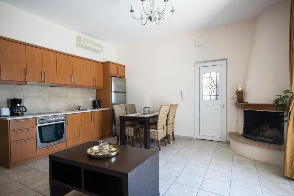 Una cocina con armarios de madera, una mesa de comedor con sillas, una cafetera y una chimenea.