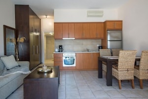 Una cocina compacta con armarios de madera, horno empotrado y zona de comedor con sillas de mimbre.
