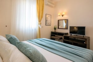 Un dormitorio con cama, televisión, escritorio y espejo.
