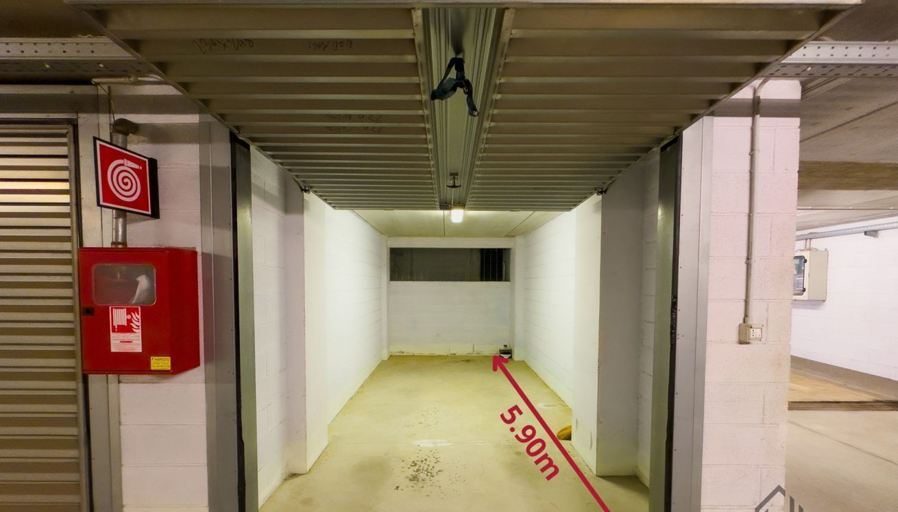 A narrow corridor with a red emergency box, a target sign, and a height marker indicating 5.90m.