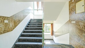 A staircase with marble walls and a view of a room with a window and curtains. - Deluxe Kaveri Road Mysore Nisarga (Mysore)