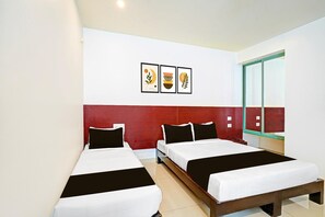 A hotel room with two beds, a red accent wall, and three framed artworks on the wall. - Deluxe Kaveri Road Mysore Nisarga (Mysore)