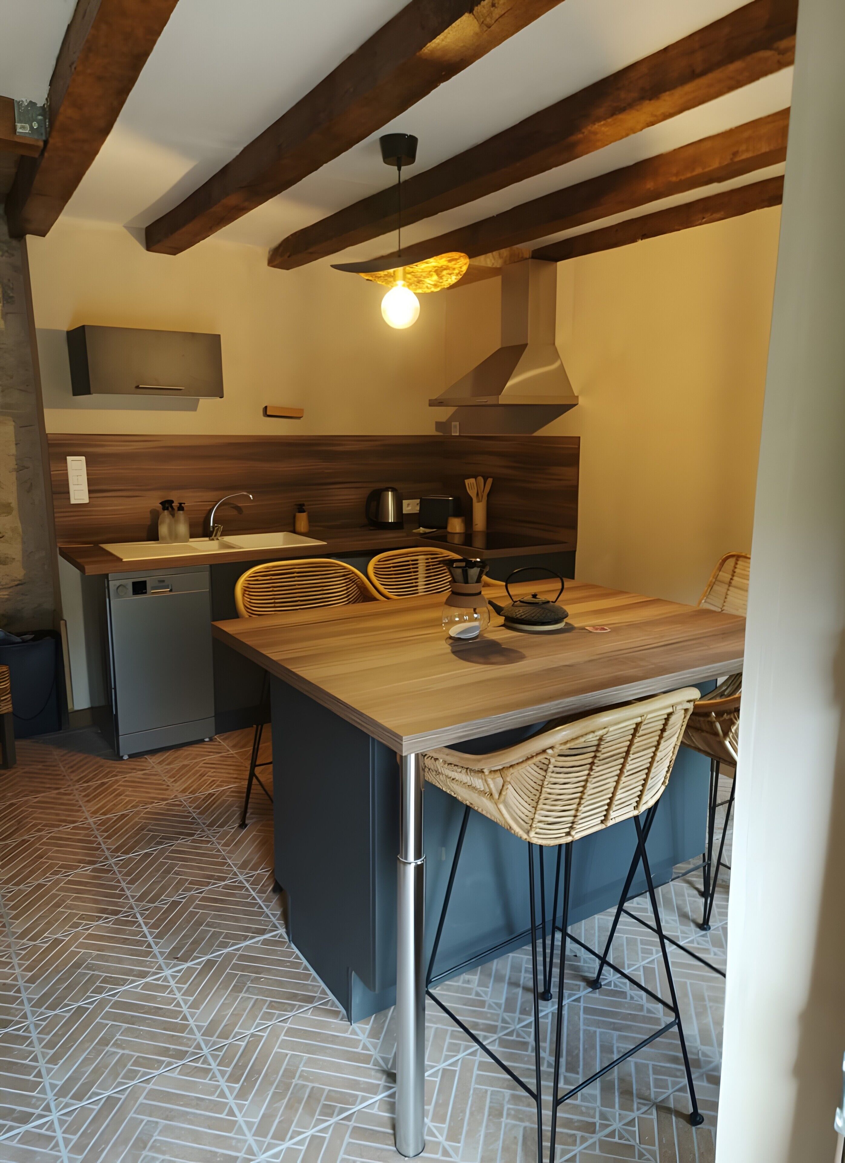 Une cuisine compacte dotée d’un îlot central en bois, d’appareils électroménagers intégrés et d’un luminaire suspendu.