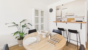 A modern dining area with a round wooden table, white plates, and black chairs. - Sea view for 2, beach 100m away (Erquy)