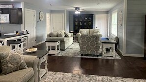A living room with a sofa, armchair, coffee table, and a television.