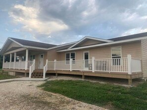 Une maison mobile à deux étages, dotée d’un porche couvert et d’une terrasse clôturée.