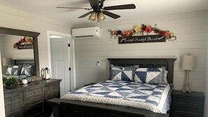 A bedroom with a bed, dresser, mirror, and a ceiling fan.