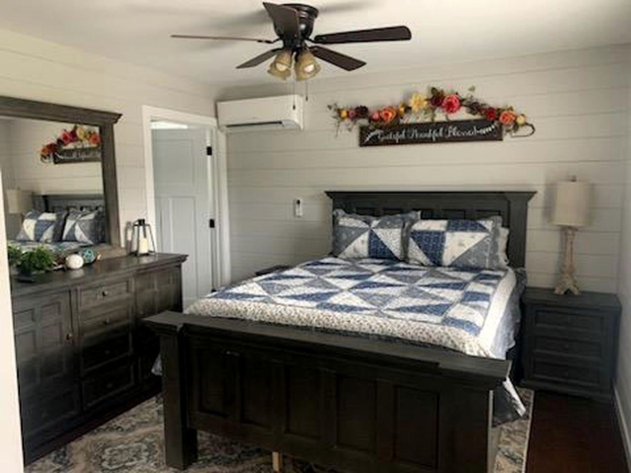 A bedroom with a bed, dresser, mirror, and a ceiling fan.