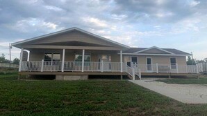 A two-story mobile home with a covered porch and a small front yard.