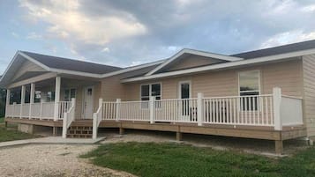 A two-story mobile home with a covered porch and a fenced deck.