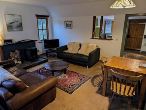 A living room with a fireplace, sofa, television, and a dining table with chairs.