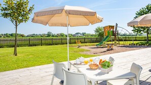Un espacio de comedor al aire libre con una mesa, sillas y una sombrilla grande.
