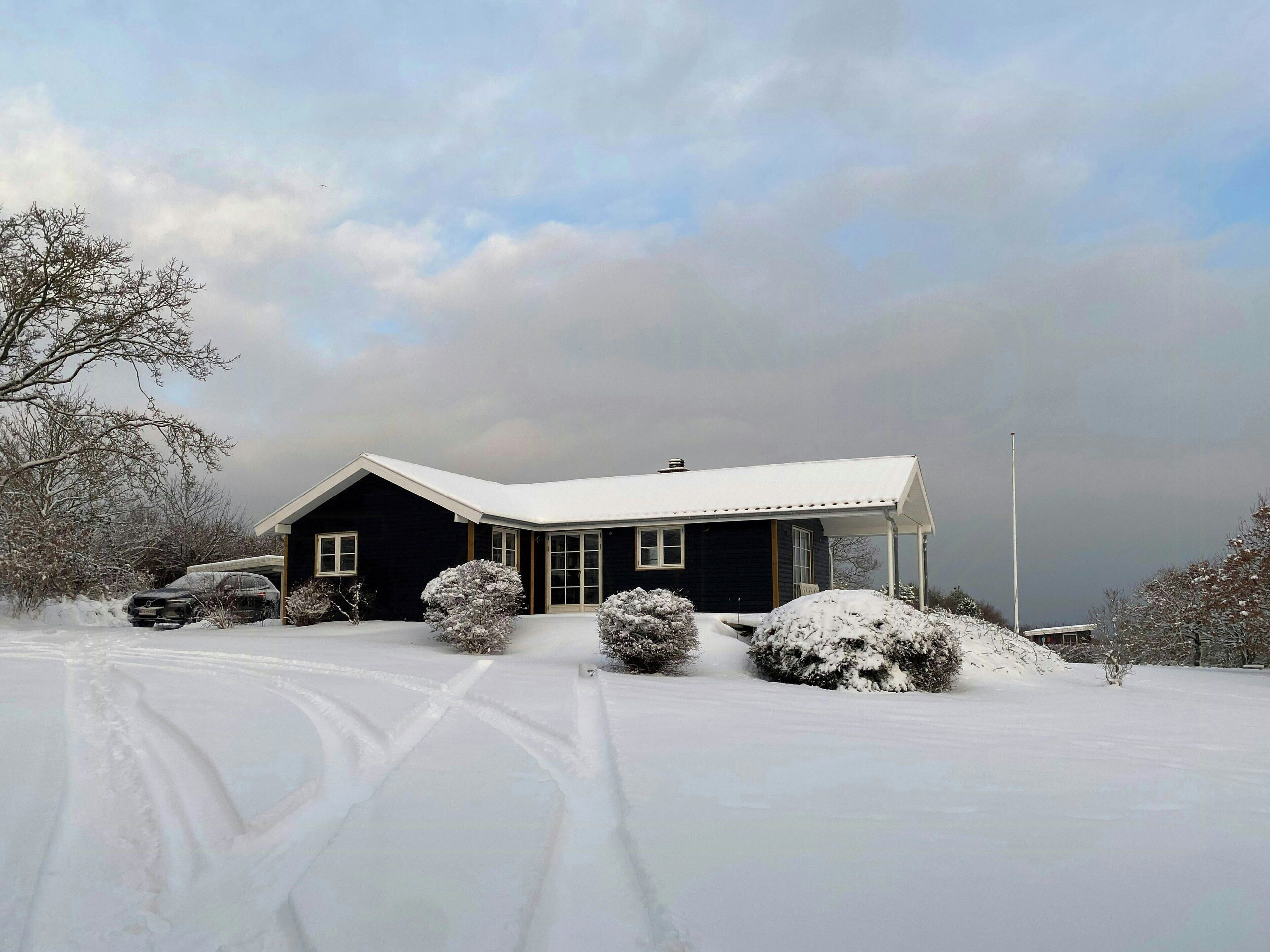 A house with a snow-covered roof, a garage, and a driveway.